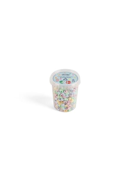 Håndfuld af små farverige perler holdes over brun bordplade med smilende perlemotiver i baggrunden.